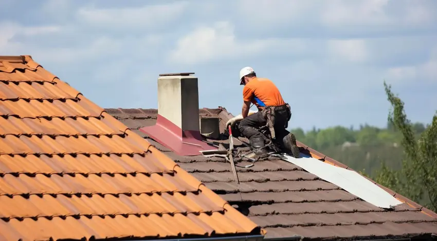 Roofer repairing chimney area on tile roof – Dallas Roofings