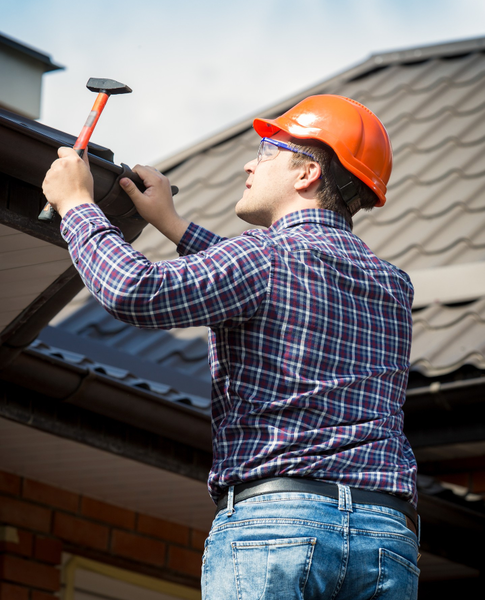 Roofer fixing roof edge with hammer – Dallas Roofings